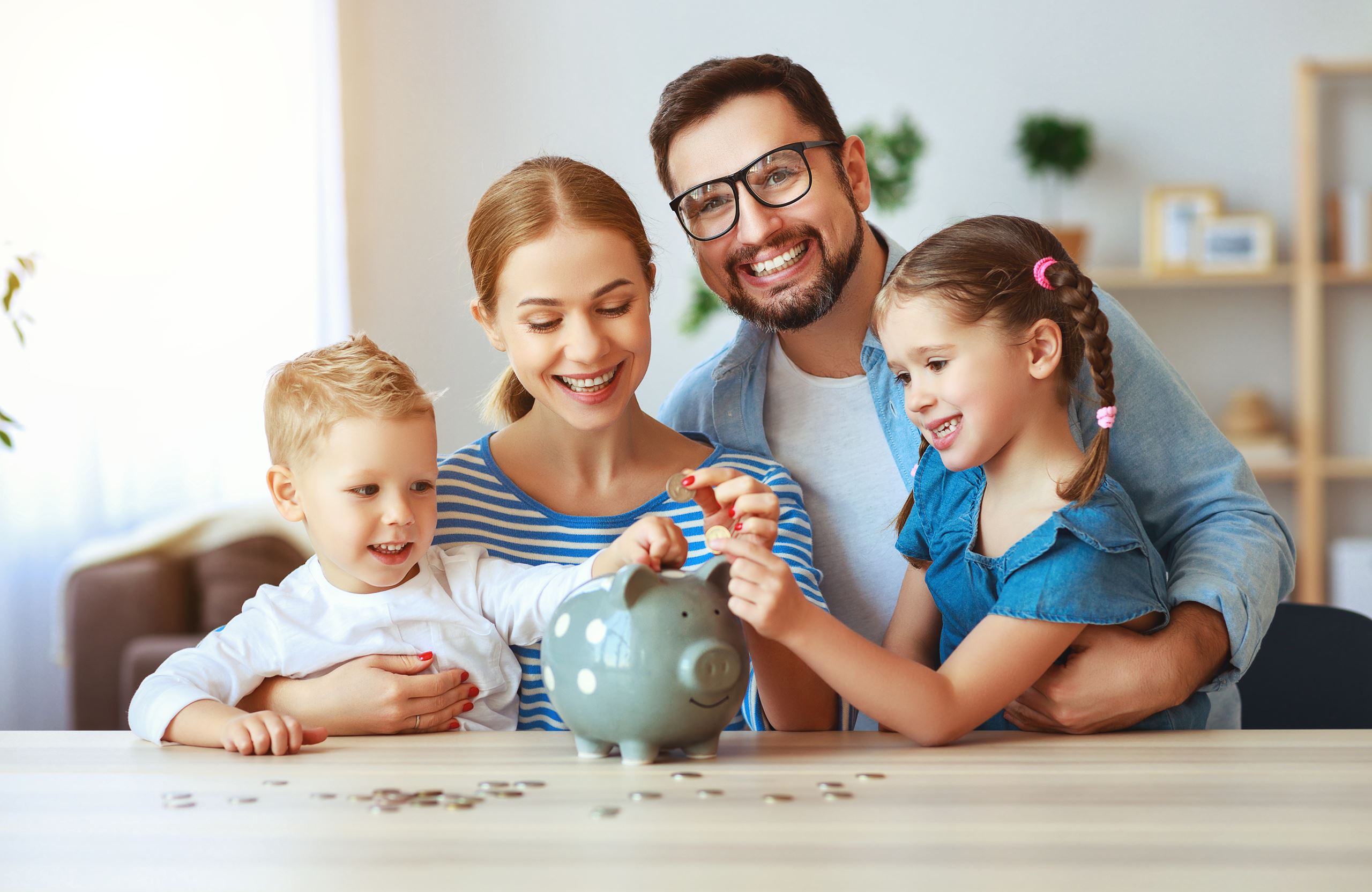 Mother, father, daughter, and son putting coins into a piggy bank